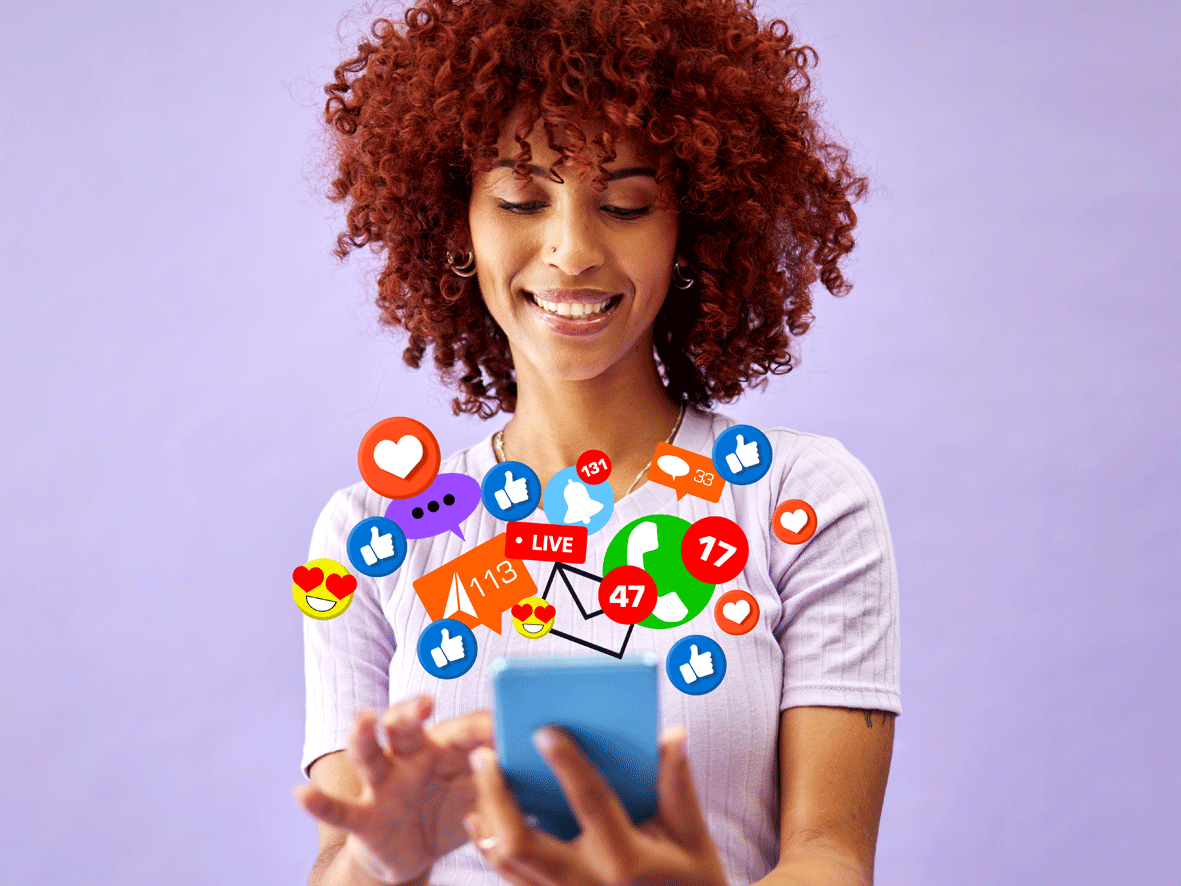 A female is looking at her mobile phone, illustrations depicting popular social media icons and emojis appear to be coming from the mobile.