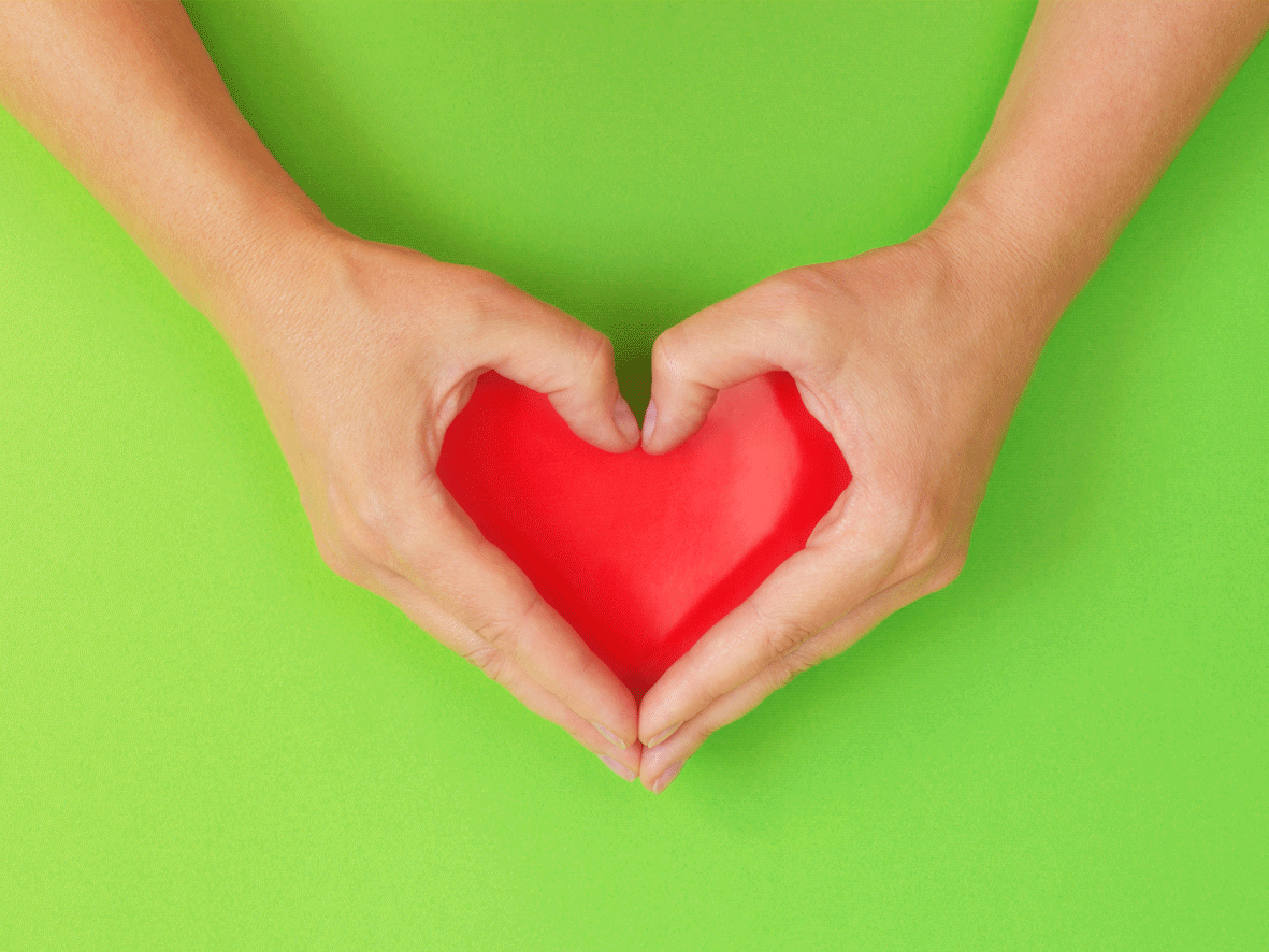 Hands are shown clasped around a red love heart. The image is used to depict positive relations between the organisation and their partners.